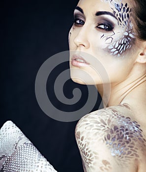 Portrait of pretty young woman with creative make up like snake, fashion victim python skin clutch