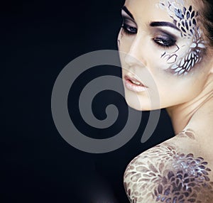 portrait of pretty young woman with creative make up like a snake, fashion victim with python skin clutch