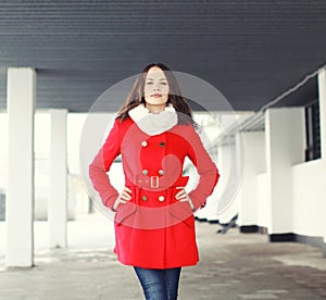 Portrait of pretty young woman dressed a red coat outdoors