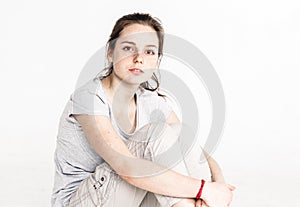 Portrait of a pretty young woman girl sitting on the floor isolated on white