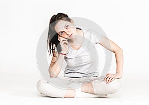 Portrait of a pretty young woman girl sitting on the floor isolated on white