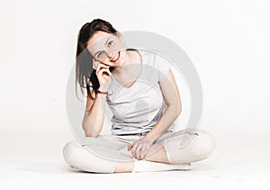 Portrait of a pretty young woman girl sitting on the floor isolated on white