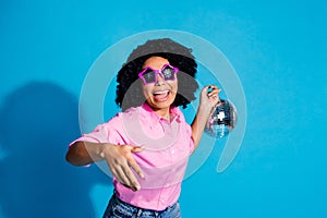 Portrait of pretty young woman hand hold disco ball dance wear pink shirt isolated on blue color background