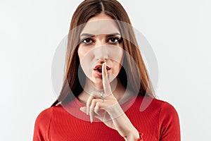 Portrait of a pretty young woman holding index finger on lips. Silence and secret concept. Studio shot, white background