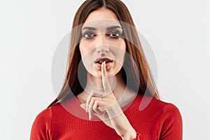 Portrait of a pretty young woman holding index finger on lips. Silence and secret concept. Studio shot, white background