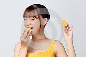 portrait of pretty young woman holding slices of orange, facial care