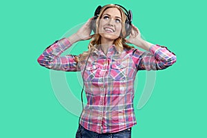 Portrait of pretty young woman listening to music in headphones and looking up.