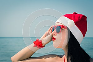 Portrait of a pretty young woman in Santa Claus hat and sunglasses