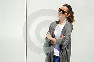 Portrait of pretty young woman smiling closeup with crosed arms over white wall