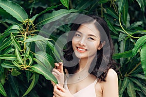 Portrait of pretty young woman standing near leaves outdoors