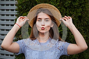 Portrait pretty young woman in summer hat blowing lips kiss outdoor