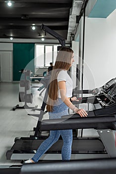 Portrait of pretty young woman taking a break from running on treadmill machine at gym