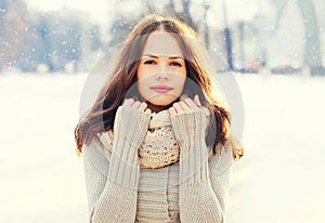 Portrait pretty young woman wearing a knitted sweater and scarf in winter over snowflakes