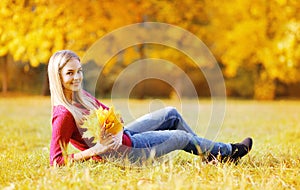 Portrait pretty young woman with yellow maple leafs outdoors in