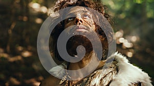 Portrait of Primeval Caveman Wearing Animal Skin Raises Hands to Heaven Looking at the Sun, Having