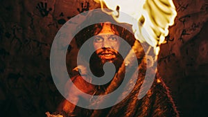 Portrait of Primeval Caveman Wearing Animal Skin Standing in His Cave At Night, Holding Torch with