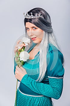 Portrait of a princess in a medieval, fantasy, turquoise dress with ash hair and a silver crown, posing with white roses in hands