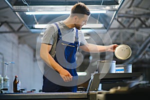 Portrait of production line worker controlling manufacturing process of modern packaging industrial machine in printing