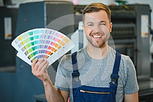 Portrait of production line worker controlling manufacturing process of modern packaging industrial machine in printing