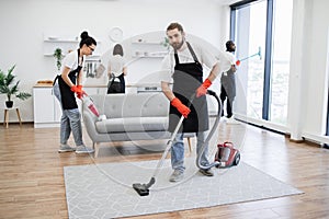 Portrait of professional bearded cleaner from cleaning service vacuums carpet.