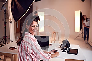Portrait Of Professional Female Photographer Working In Studio With Assistants