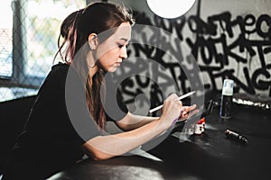 Portrait of a professional female tattooist in a tattoo studio draws a sketch on a tablet