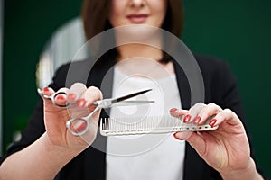 Portrait of professional hairdresser in beauty salon. Close-up picture of work accessories instruments - scissors and comb in