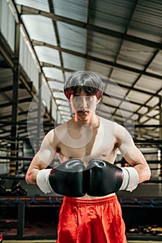Portrait of professional male boxer against boxing training ground background