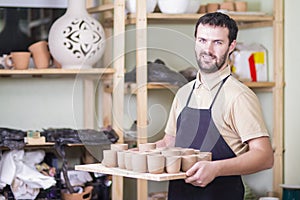 Portrait of Professional Male Ceramist Holding Tray with Clay Cups