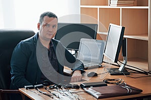 Portrait of professional polygraph examiner in the office with his lie detector`s equipment