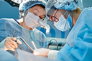 Portrait of professional surgeons during surgery on a blue background. Concept surgery, medicine. Surgeons are working
