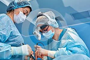 Portrait of professional surgeons during surgery on a blue background. Concept surgery, medicine. Surgeons are working