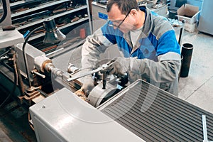 Portrait of professional turner at work on lathe in workshop.