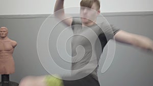 Portrait of a professional young man in gloves punching and kicking the air, showing his skills in the gym close up