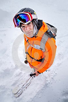 Portrait of a professional young skier in a ski helmet mask and a backpack on skis. The concept of winter sports