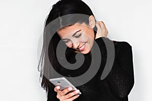 Portrait in profile of attractive young happy woman using smart phone with healthy toothy smile