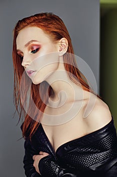 Portrait profile of a womans face with red bright hair. Hair coloring, color. Naked girl in a black leather jacket. Perfect makeup