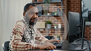 Portrait of programer typing programming code on computer keyboard turning head and smiling