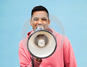 Portrait, protest and megaphone with a man in studio on a blue background for an announcement or speech. Freedom, human