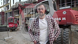 Portrait of proud builder at construction site. Constructor with excavator prepared to start building new house