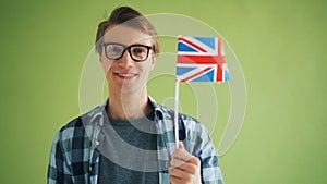 Portrait of proud englishman holding flag of England smiling looking at camera