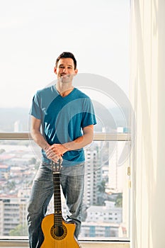 Portrait Of Proud Man Holding Classic Guitar And Smiling