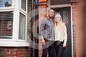 Portrait Of Proud Young Couple Standing Outside First Home Together photo