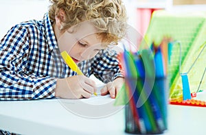 Portrait of pupil in school class taking notes during writing lesson. Education, childhood, homework and school concept.