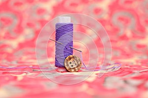 Portrait of purple sewing thread, needle and button