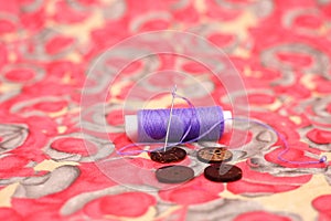 Portrait of purple sewing thread, needle and button