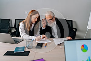 Portrait of puzzled diverse-ages male and female colleagues discussing information during cooperation briefing in office