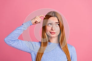 Portrait of puzzled girl with foxy hairdo wear blue pullover finger on head look at offer empty space isolated on pink