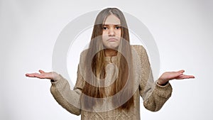 Portrait of puzzled girl lost and looking for something in pockets over white studio background