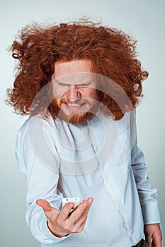 Portrait of puzzled man talking on the phone on a gray background